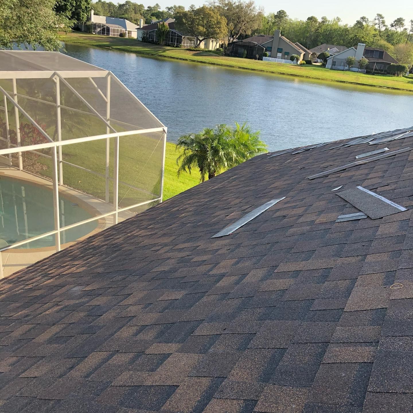 A roof with a screened in pool and a lake in the background