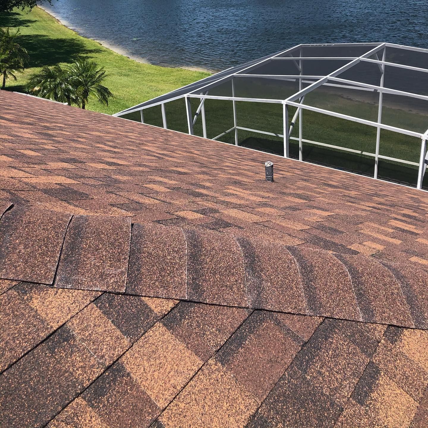 A roof with a screened in pool and a view of a lake