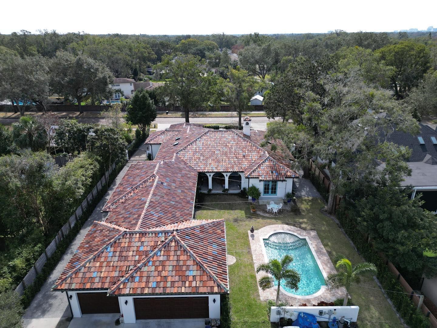 An aerial view of a large house with a pool in the backyard surrounded by trees