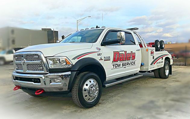 White tow truck with red decals parked outdoors on a cloudy day.