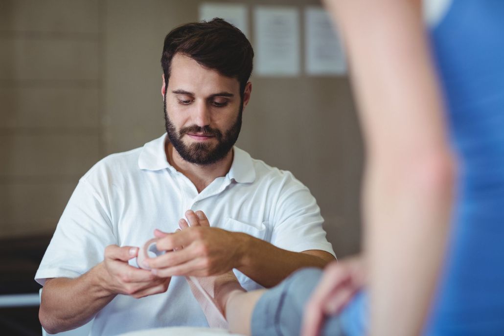 Man applying tape to another person’s finger in a clinical setting.