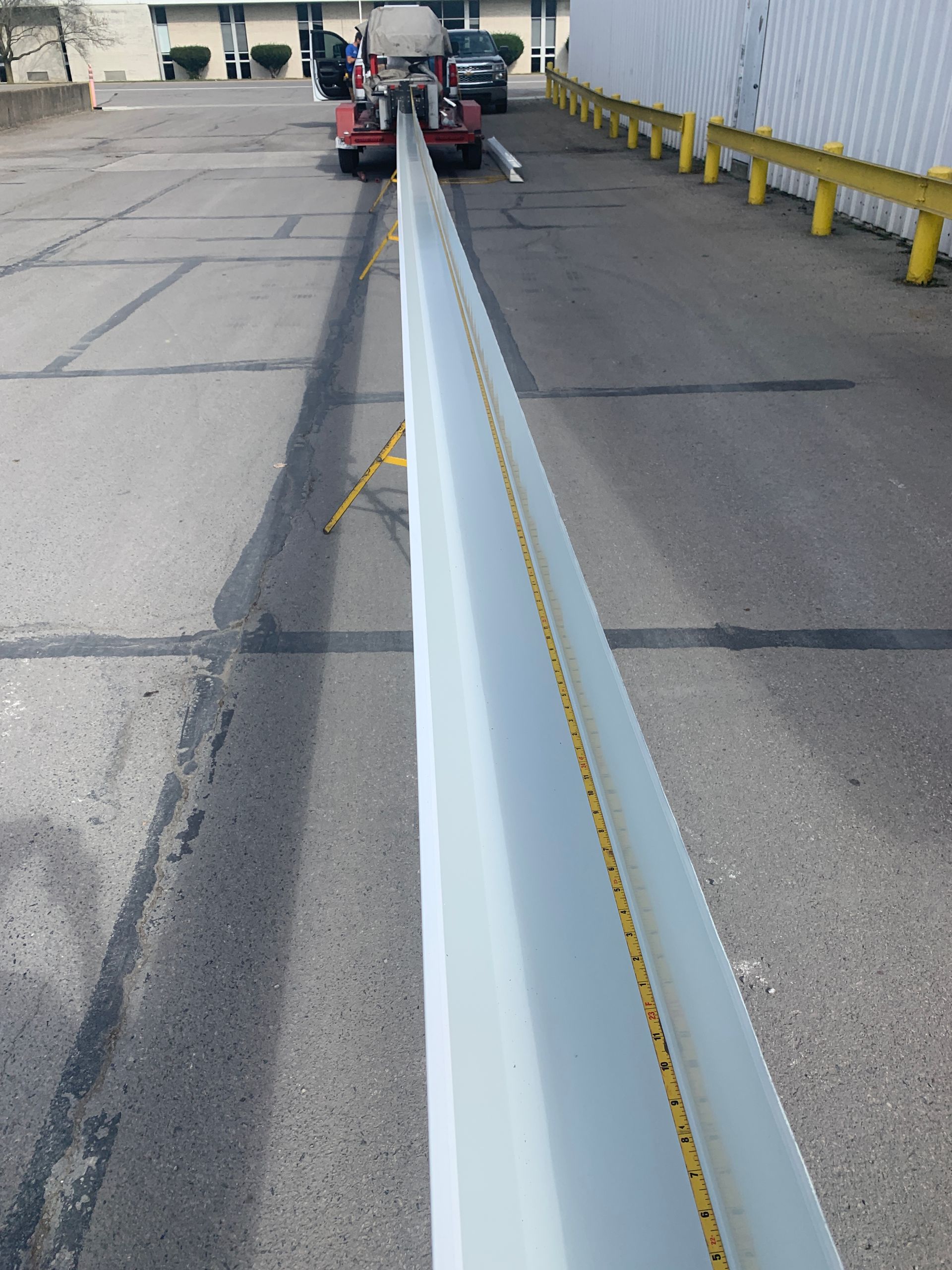 Long white beam being carried on a truck down an industrial roadway