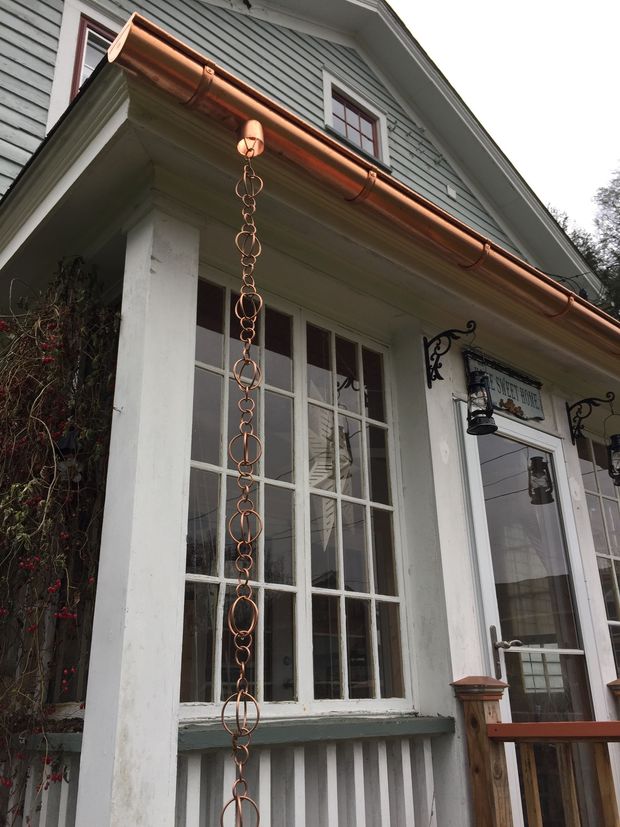 Front porch with white-trimmed windows, hanging chain, and a small wooden railing on a house exterior.