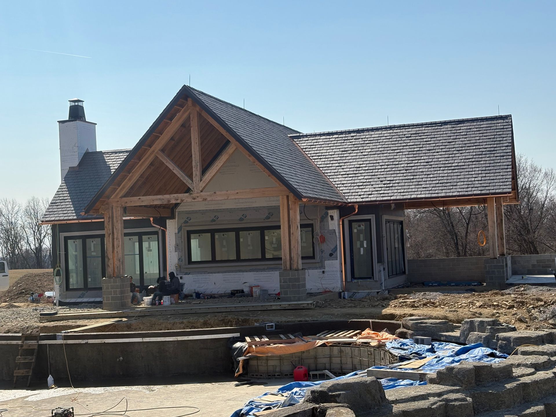 Unfinished house with exposed framing and a snow-covered yard on a winter day