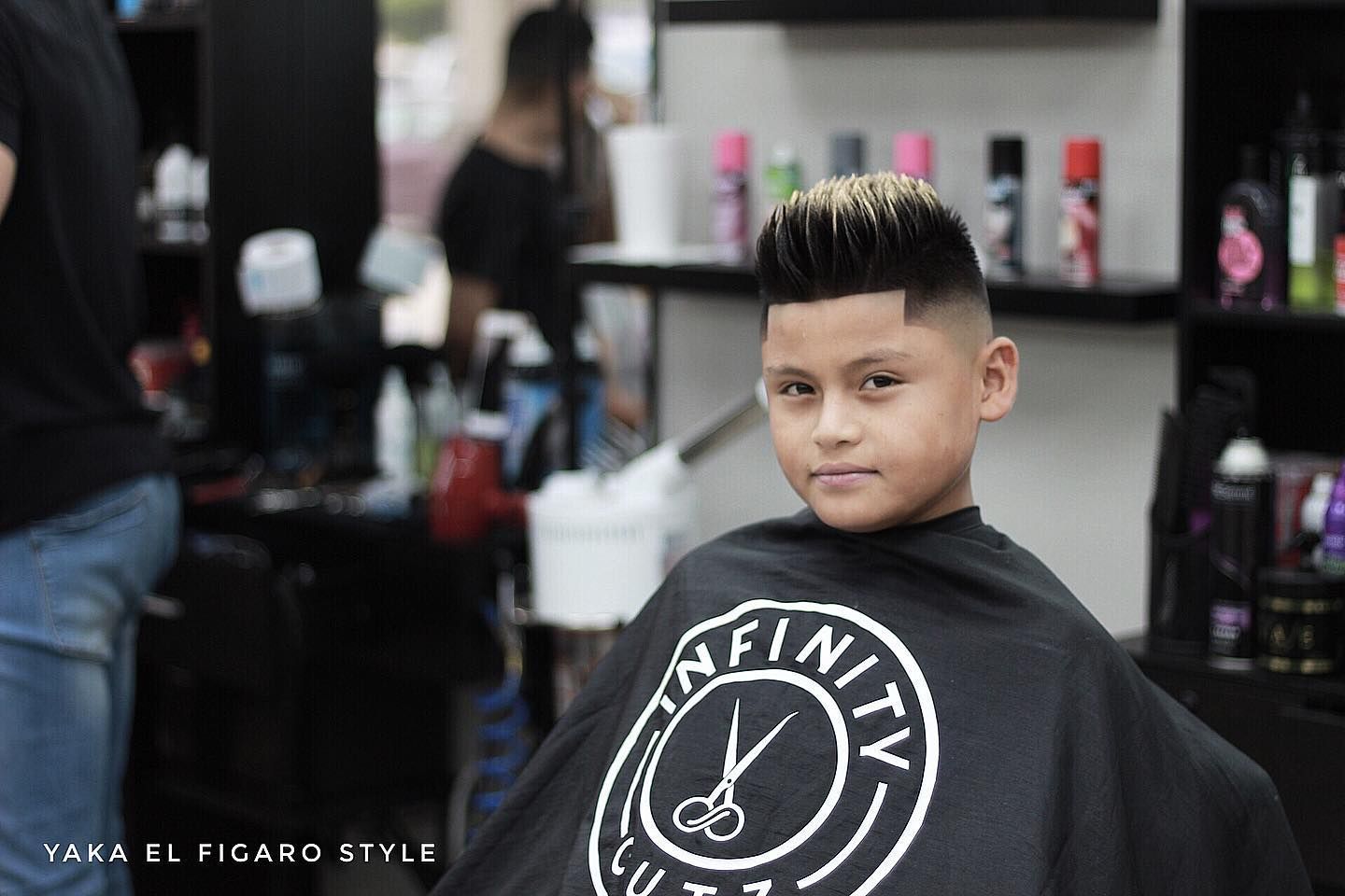 A young boy is getting his hair cut at a barber shop.