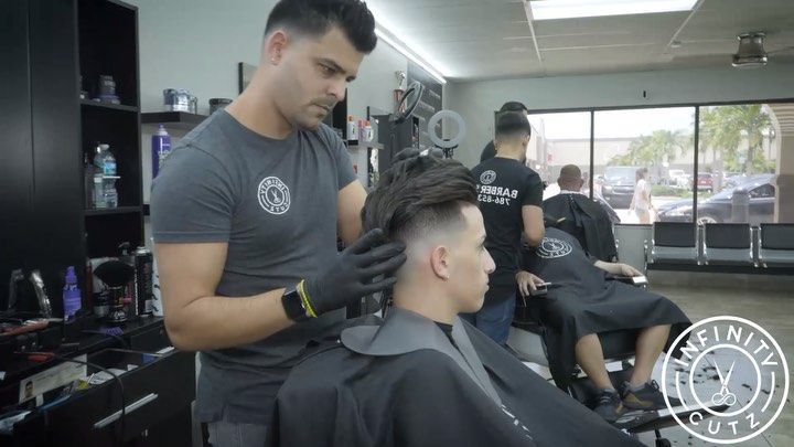 A man is cutting a man 's hair in a barber shop.
