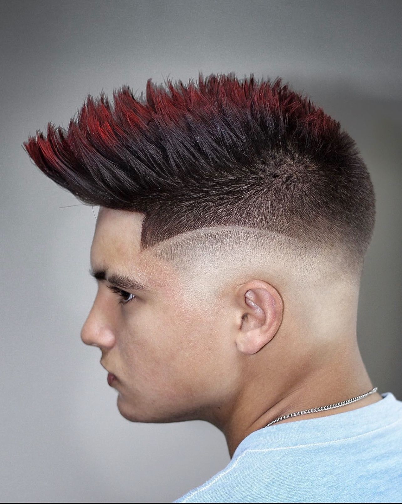 A man with a mohawk hairstyle is wearing a blue shirt.