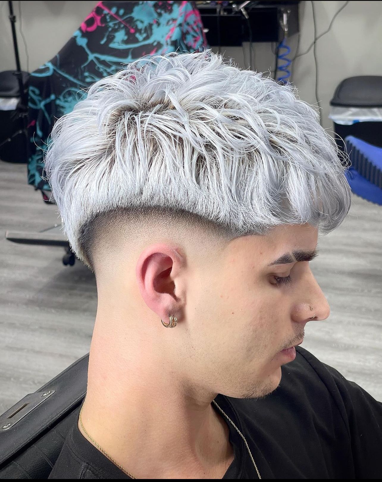 A man with silver hair is getting his hair cut at a barber shop.