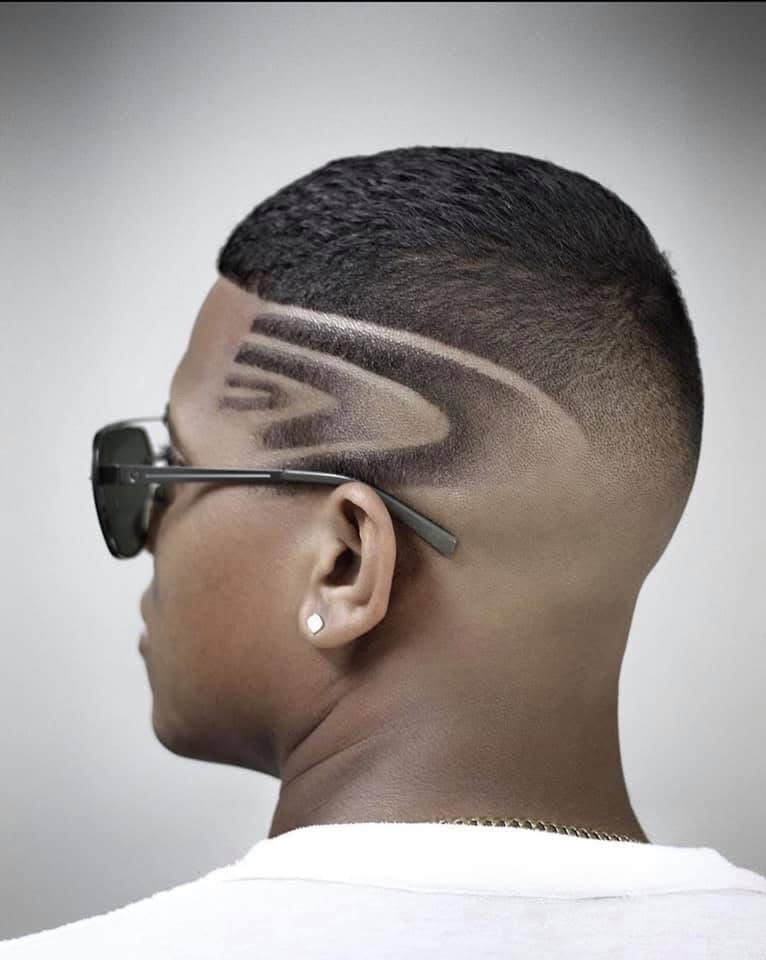 A man wearing sunglasses has a design on his hair