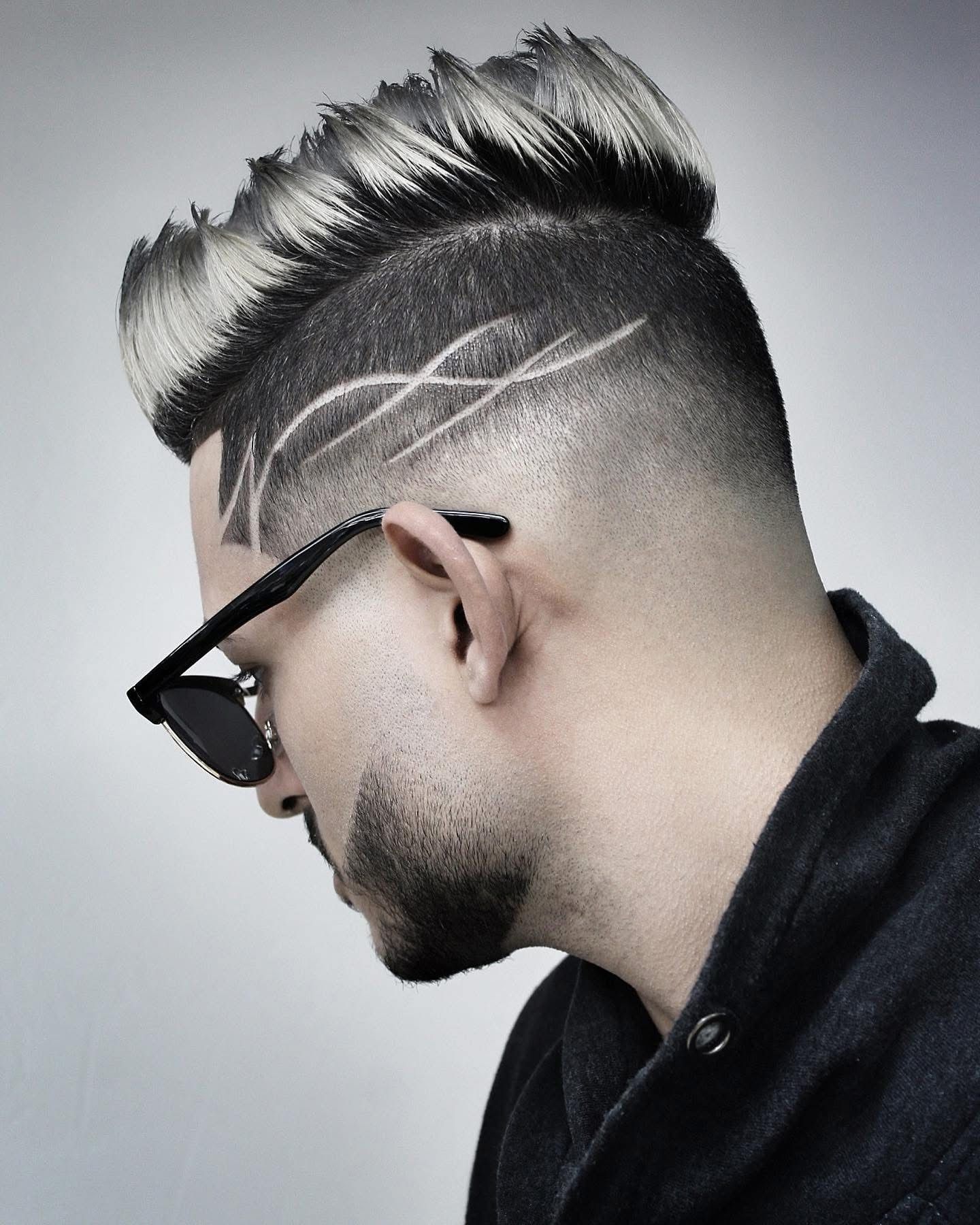 A man with a beard and sunglasses has a design in his hair.