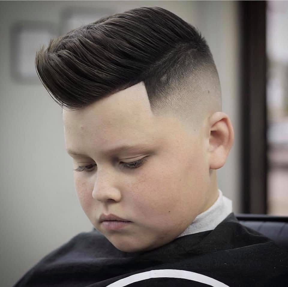 A young boy is getting his hair cut at a barber shop.