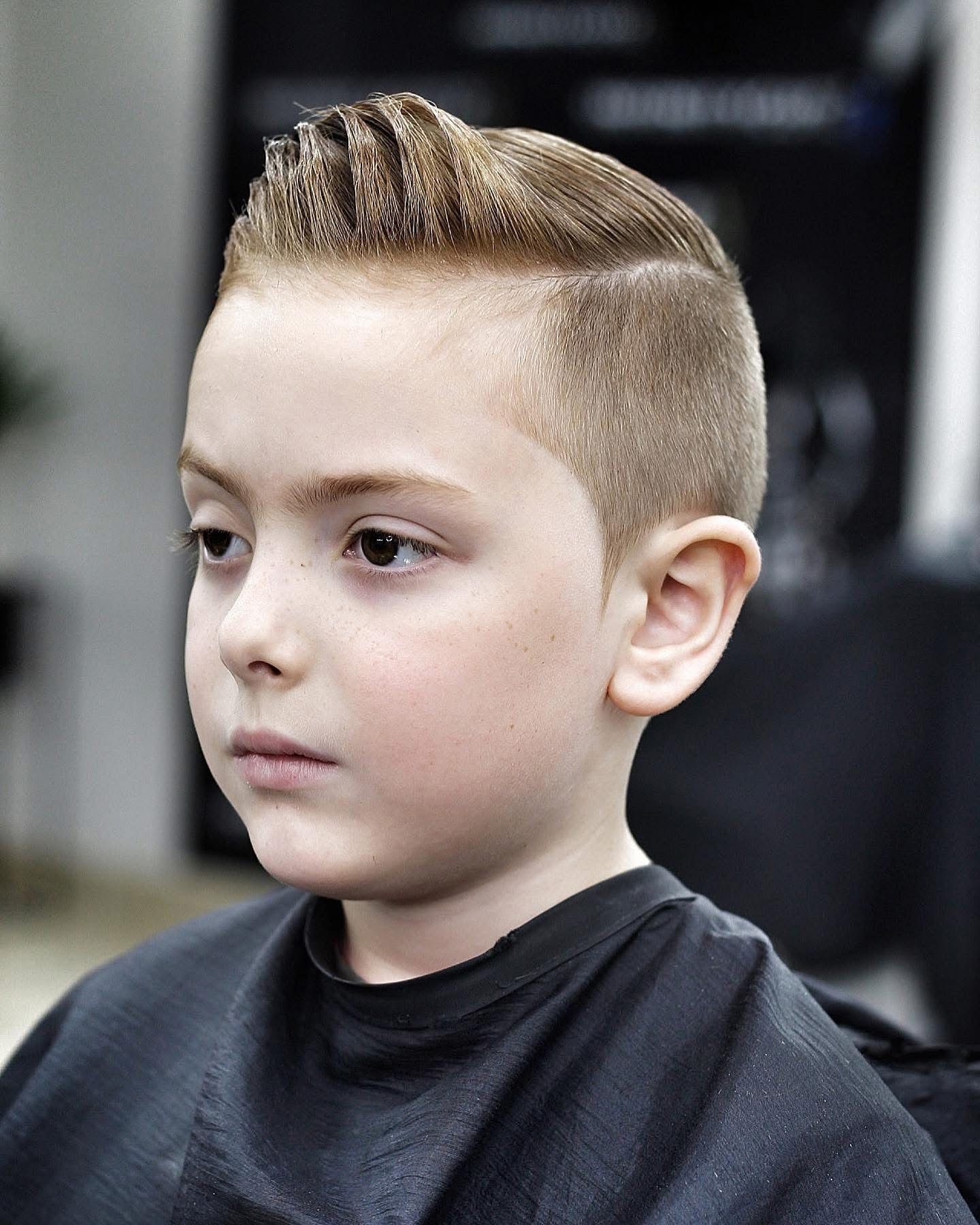 A young boy is getting his hair cut at a barber shop.