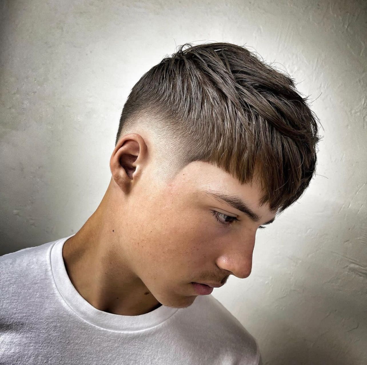 A young man with a fade haircut is wearing a white shirt