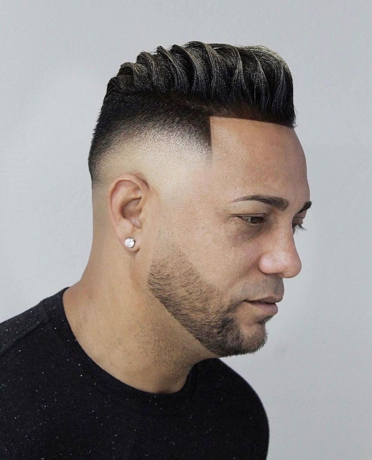 A man with a beard and earrings is wearing a black shirt