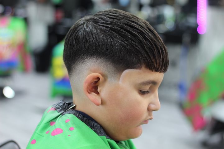 A young boy is getting his hair cut at a barber shop.