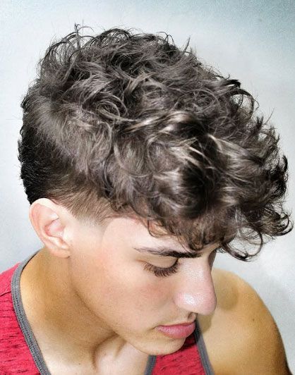 A young man with curly hair is wearing a red tank top.