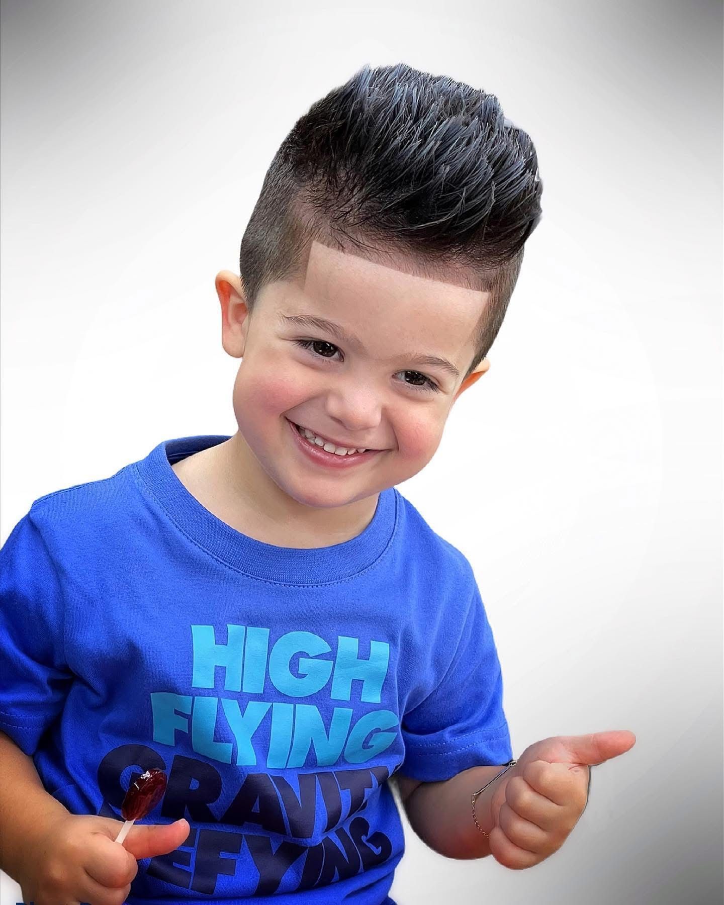 A young boy wearing a blue shirt that says high flying