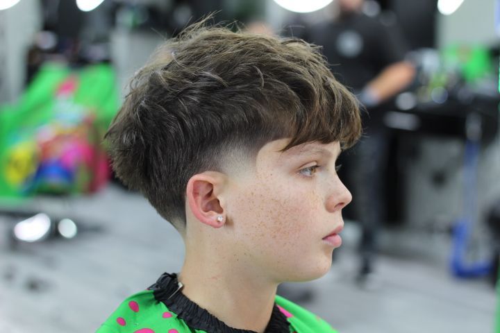 A young boy is getting his hair cut at a barber shop.