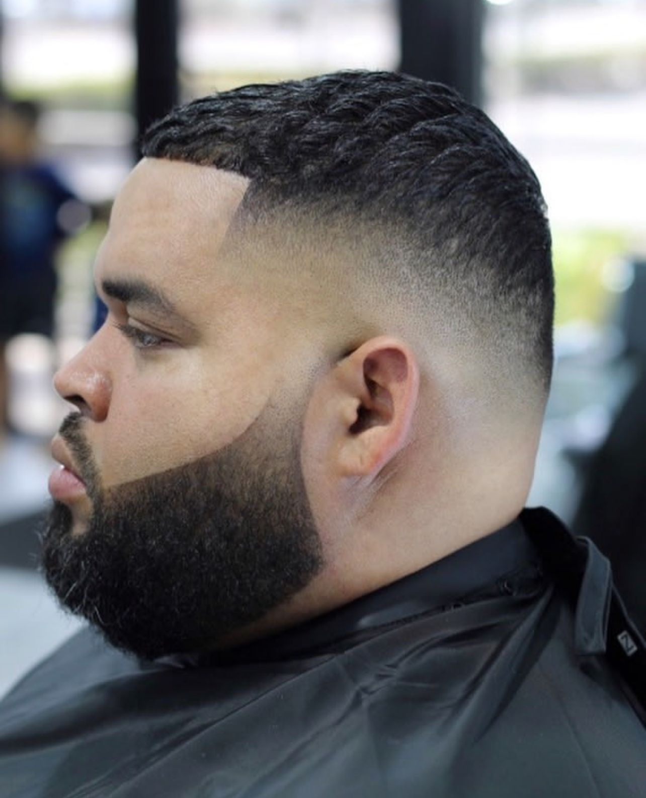 A man with a beard is getting his hair cut at a barber shop