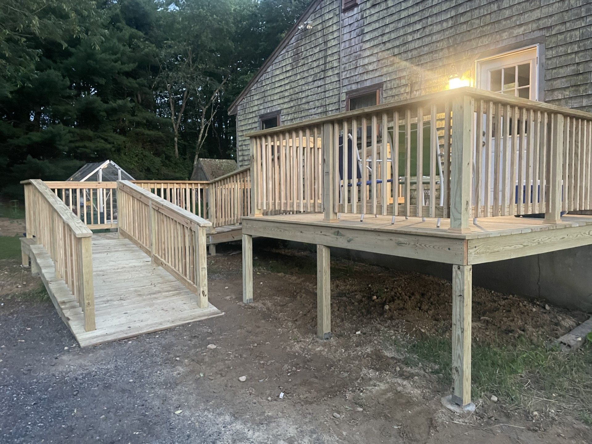 Wooden accessibility ramp and elevated deck beside a house at dusk