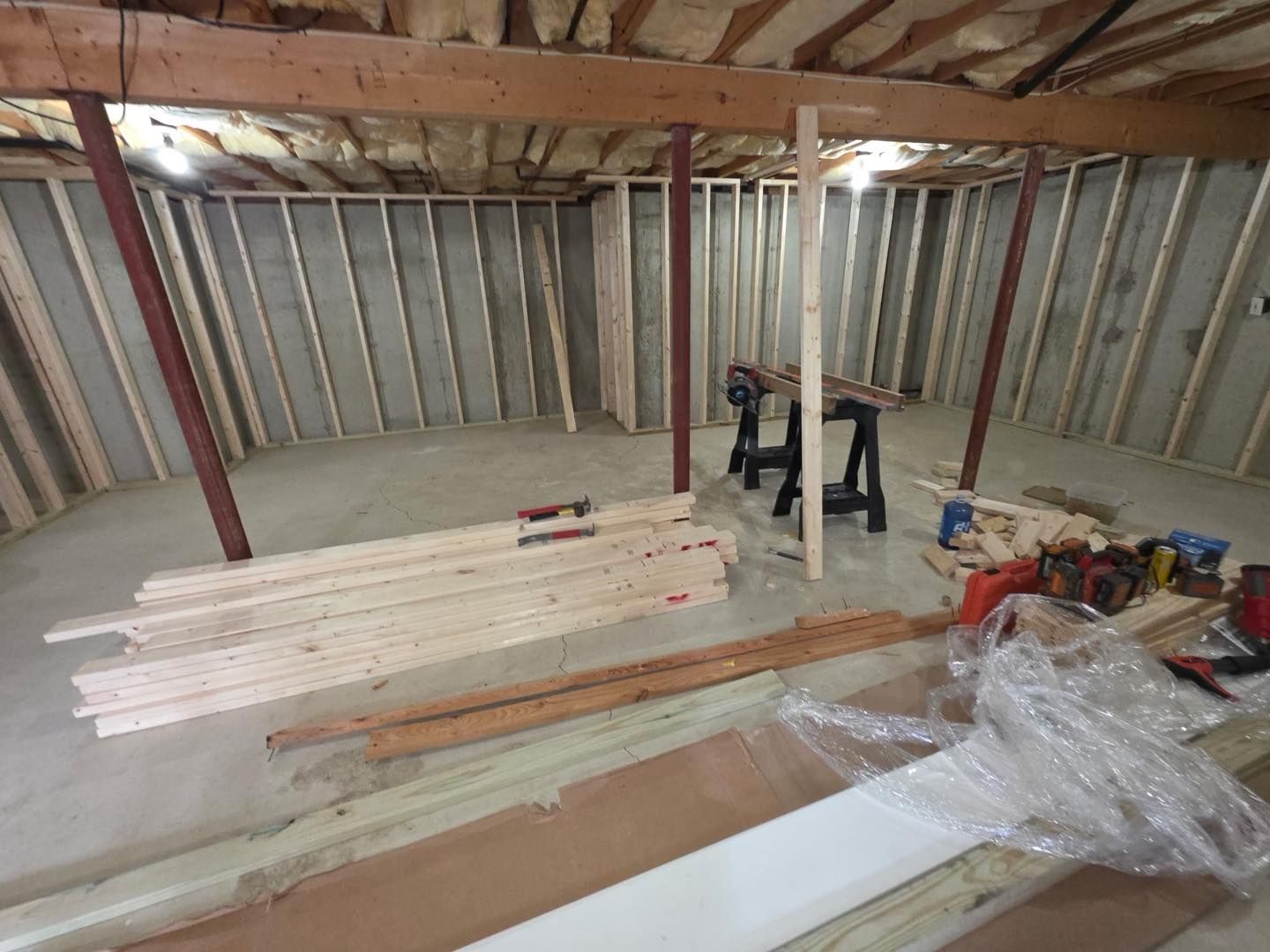 Partially built attic with exposed beams, stacked lumber, and tools on the floor