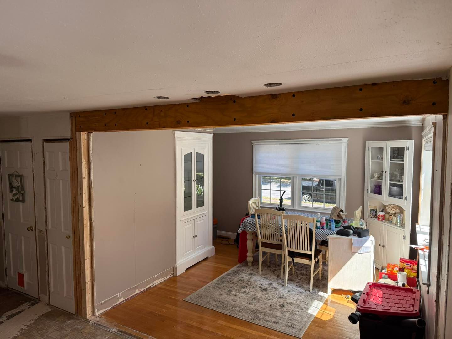 Interior view of a home with a dining area, white doors, gray walls, and exposed wooden beam overhead
