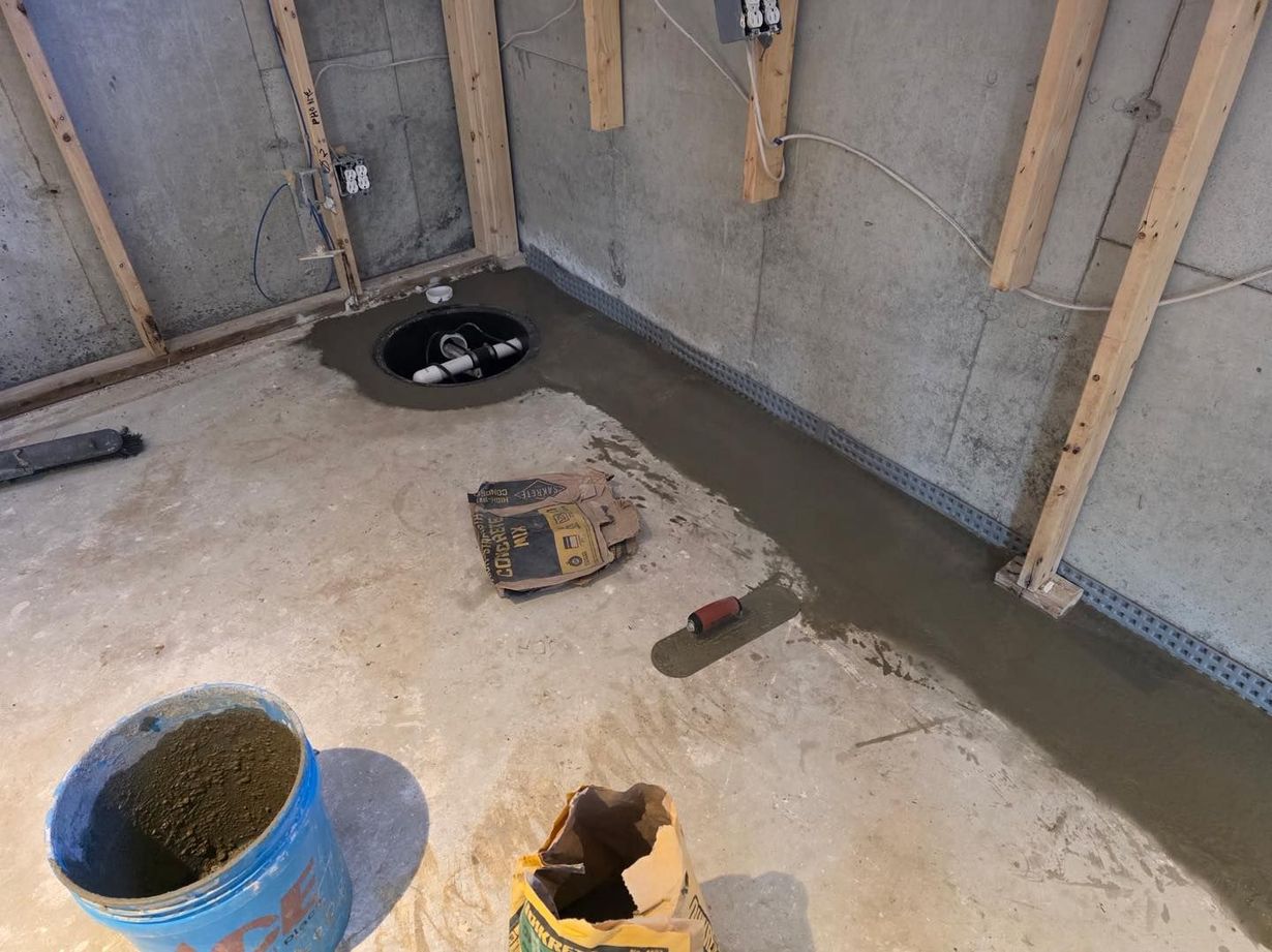 Partially finished bathroom floor with exposed wall framing and construction tools