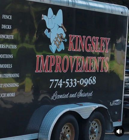 Black trailer with Kingsley Improvements logo, phone number, and exterior home improvement services listed on the side