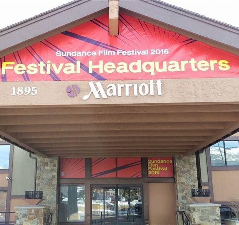 Sundance Film Festival 2016 headquarters at a Marriott, red banner, brown roof, stone facade, glass doors.