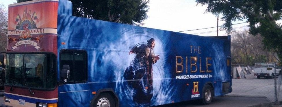 Two buses parked outdoors; one is promoting