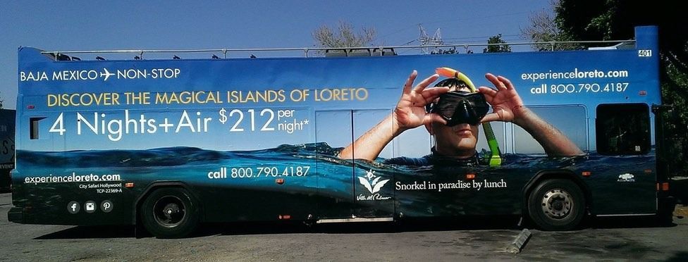 Double-decker bus advertisement promoting a trip to the magical islands of Loreto, with a diver.