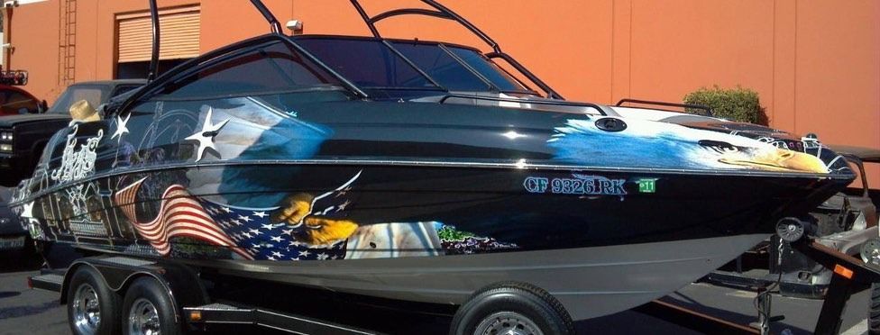 Black boat with American flag and eagle graphics, on a trailer.