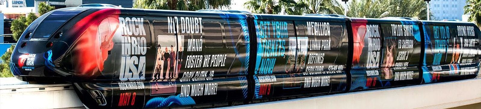 A monorail train with colorful advertisements traveling through a city.