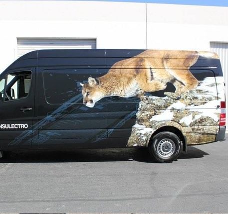Black van with a cougar leaping across a snowy rock face.