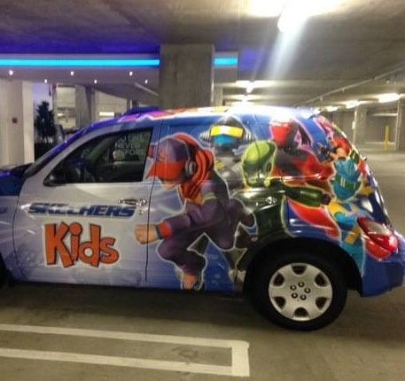 Skechers Kids-branded PT Cruiser, with cartoon characters, in a parking garage. Blue, red, and white color scheme.
