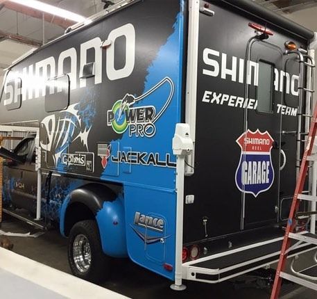 Shimano-branded RV; black, blue, and white; parked inside. Logos include Power Pro, Garage, and others.