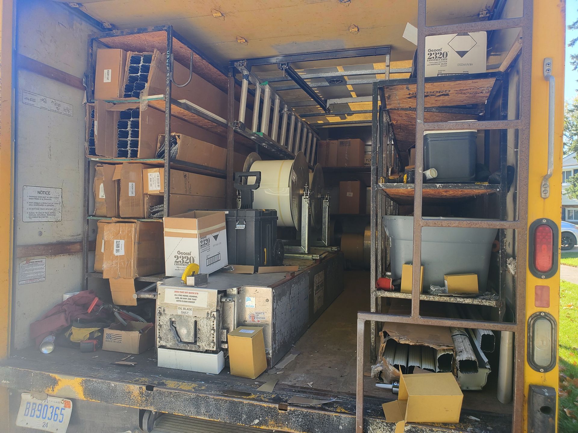 The back of a yellow truck filled with boxes and shelves.