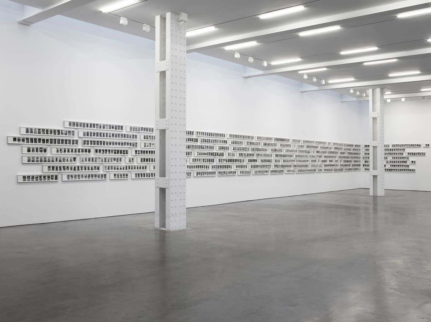White gallery space with text on walls. Text is arranged on white rectangular panels.