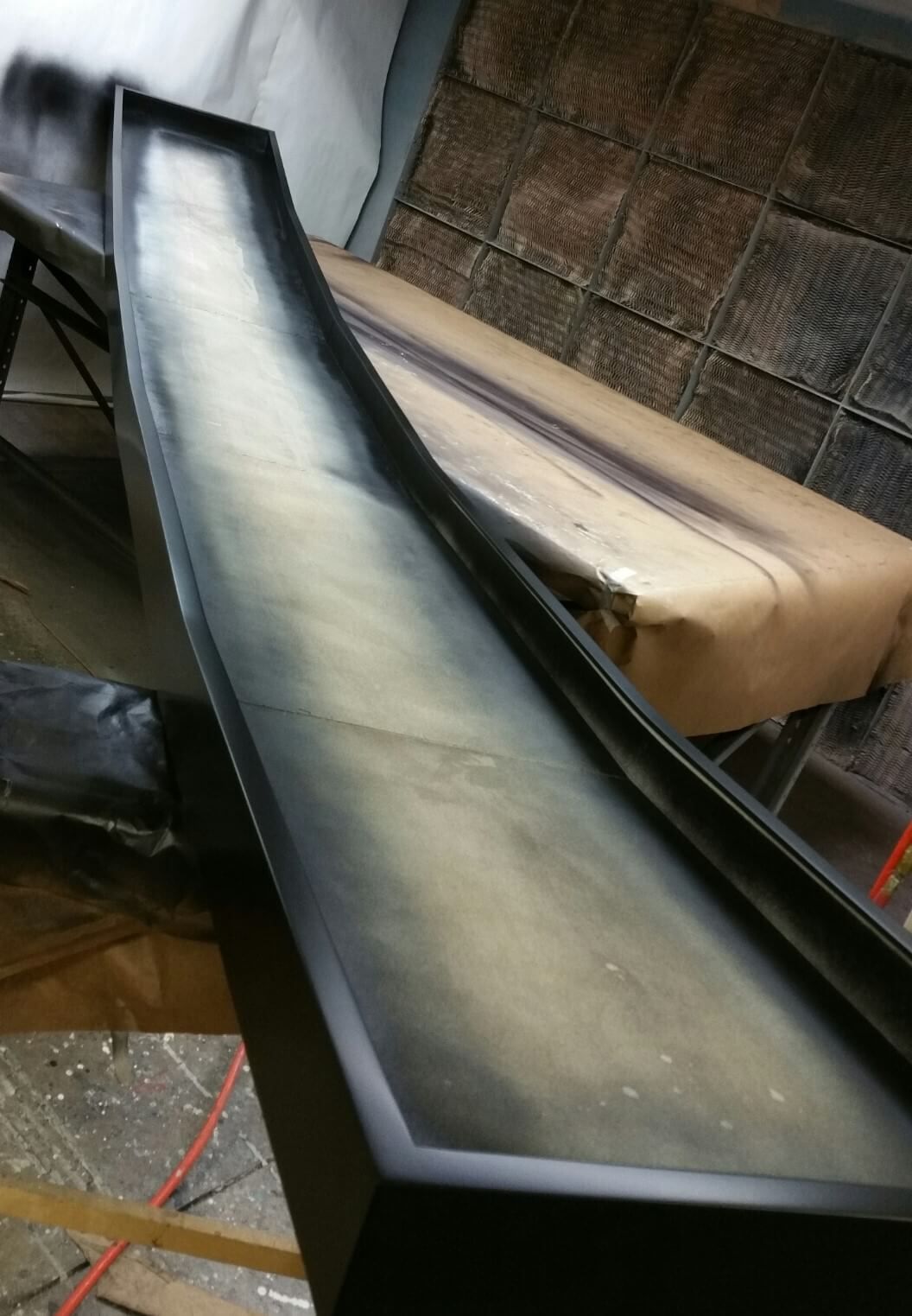 Black painted trough with light interior, possibly for a project, on a workspace.