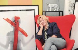 Woman in red chair, smiling. Beside a Marilyn Monroe photo with red X. White tiger statue.