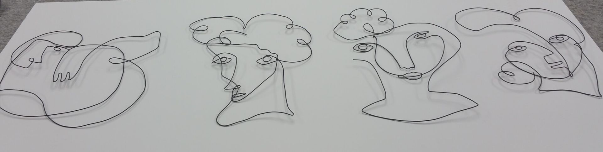 Four wireframe portraits on a white surface, each depicting a face with facial features.