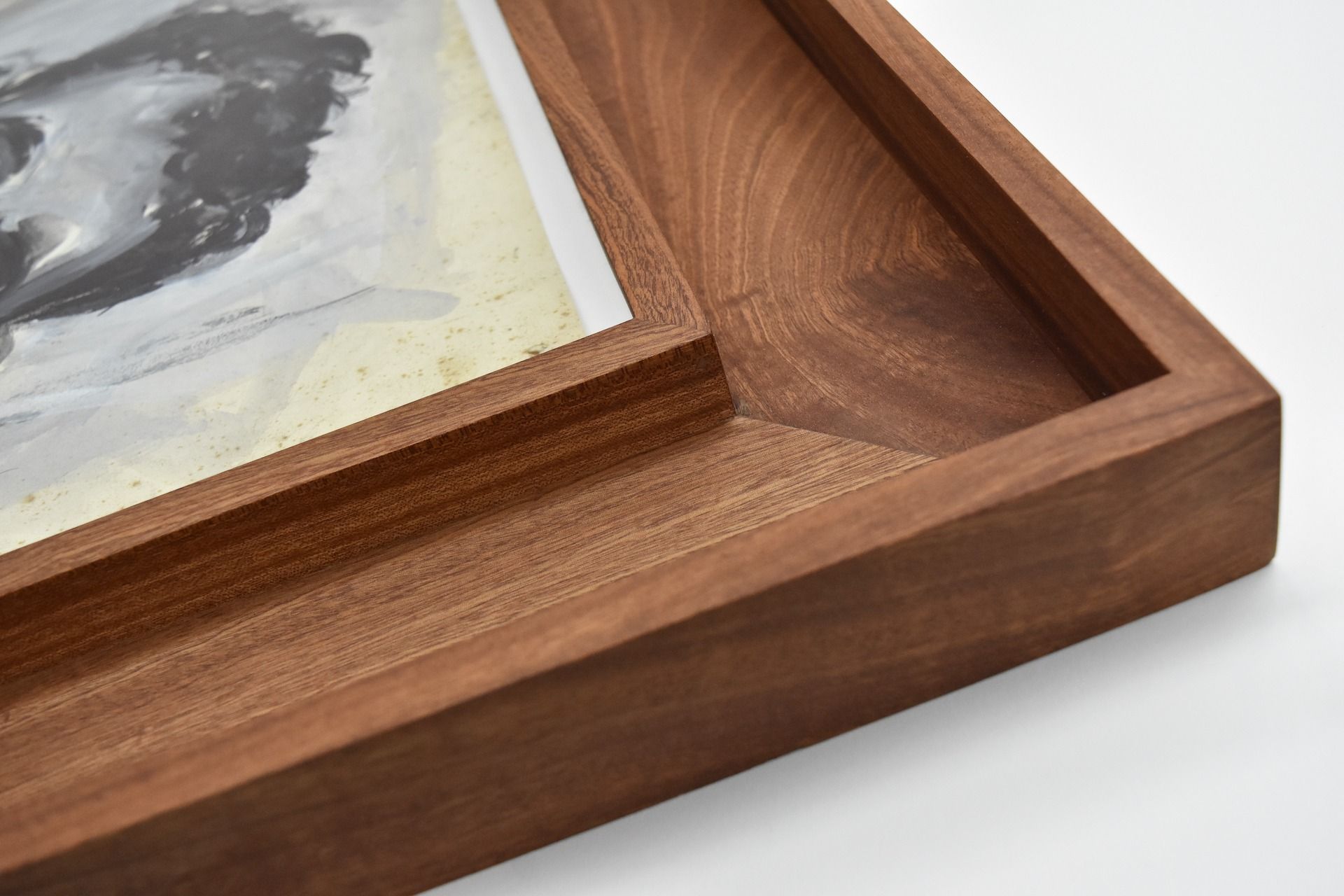 Close-up of a wooden art frame, holding a monochrome painting with a white mat.