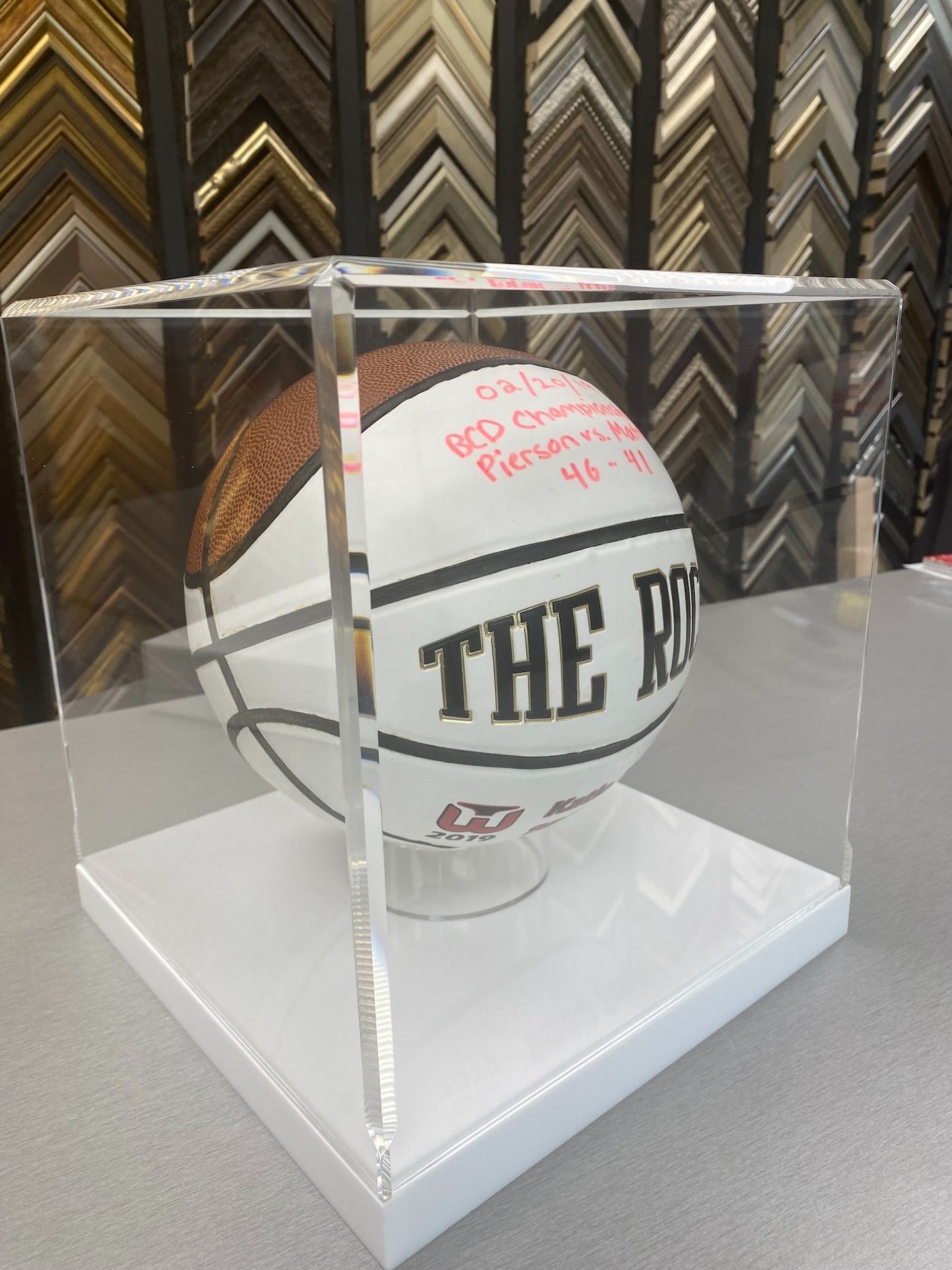 Basketball inside a clear display case on a white base, with text reading 