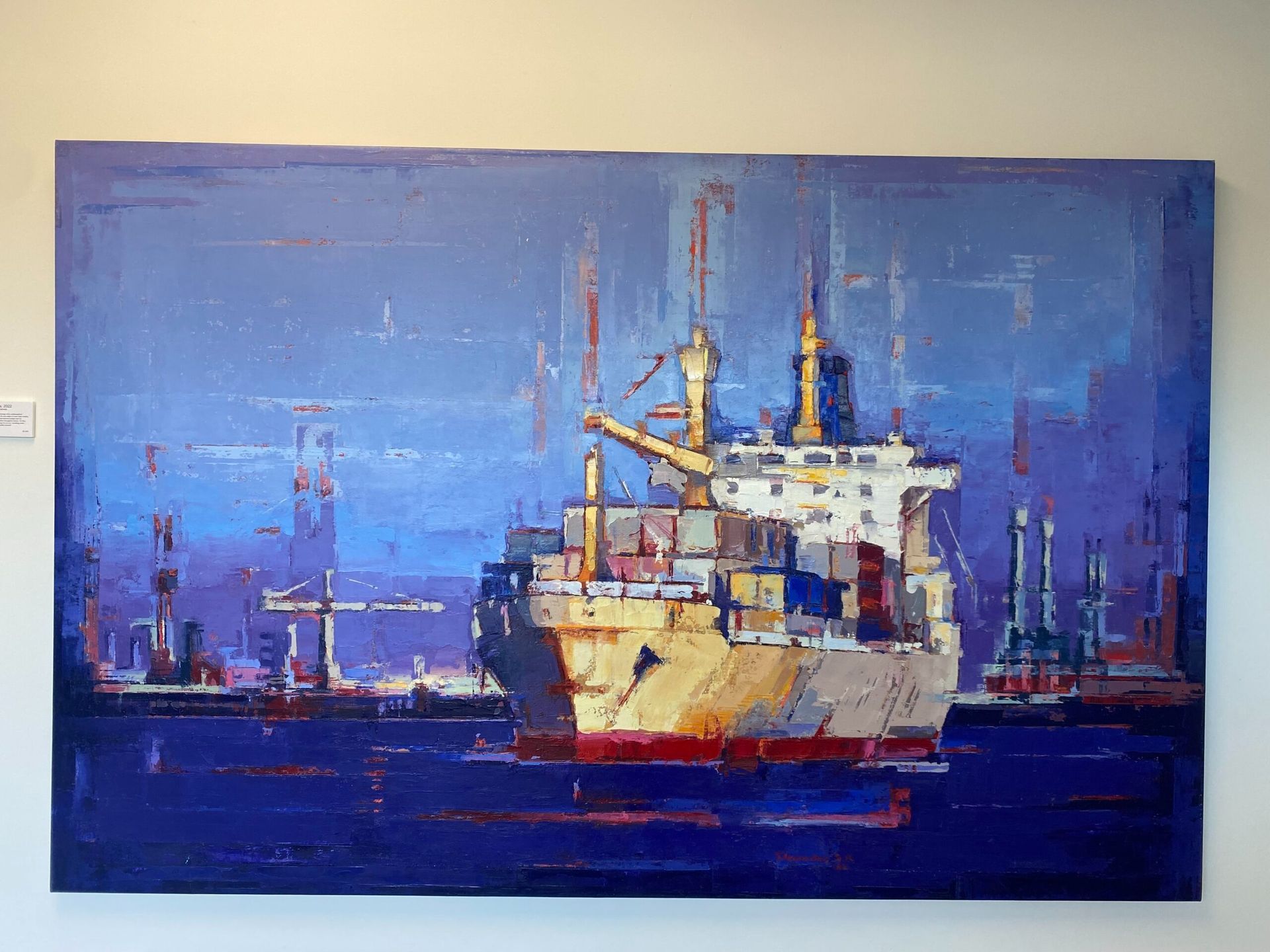 Large oil painting of a cargo ship in a blue harbor. The ship is yellow, red, and white.