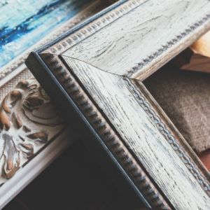 Close-up of decorative wooden picture frames, some white, brown, and ornate.