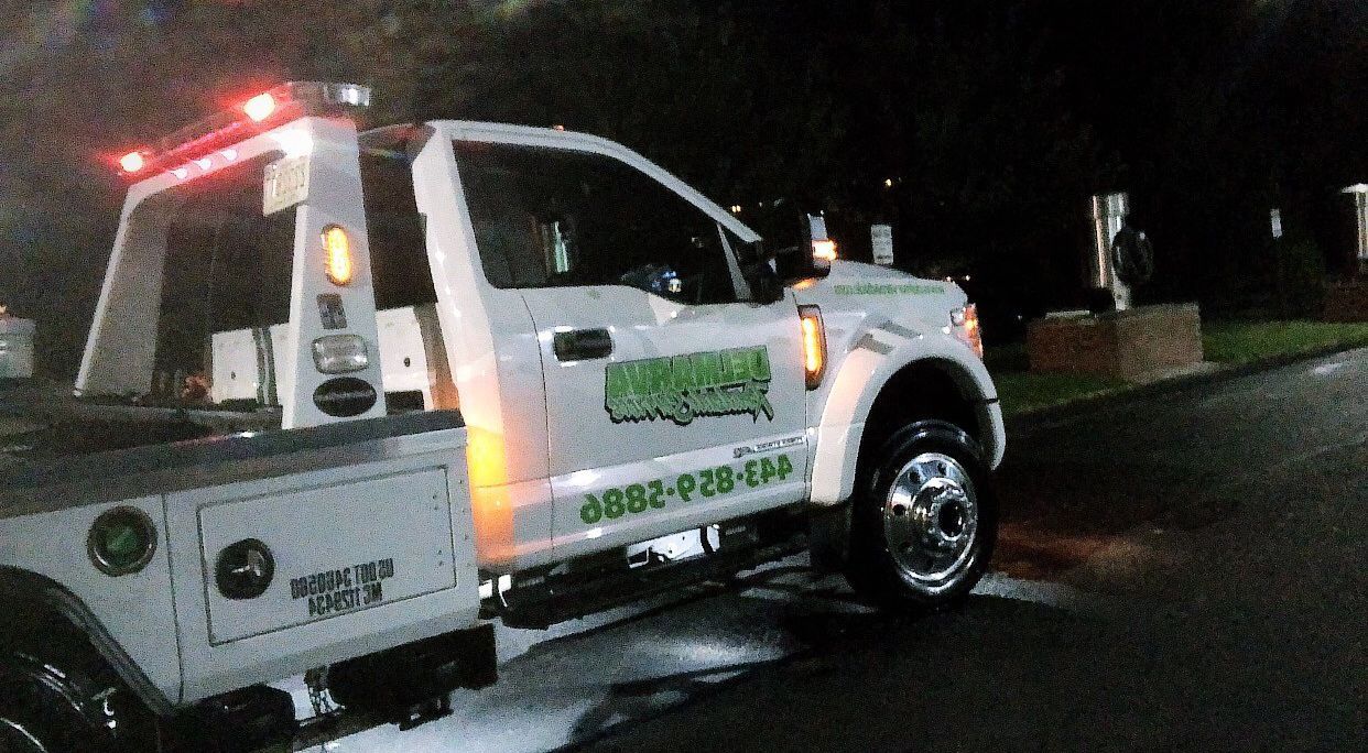 a white tow truck is parked on the side of the road at night.