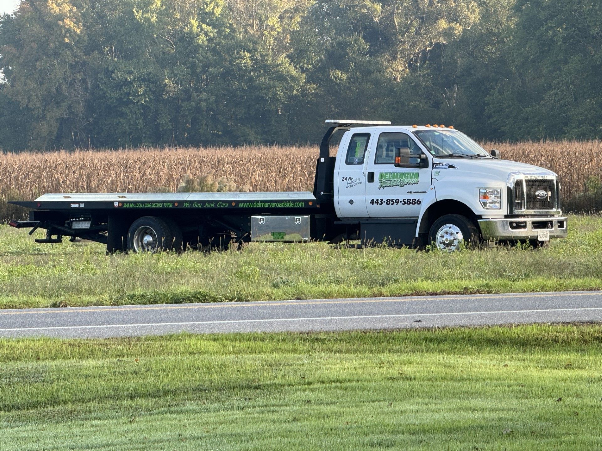 a tow truck is parked on the side of the road in a grassy field.