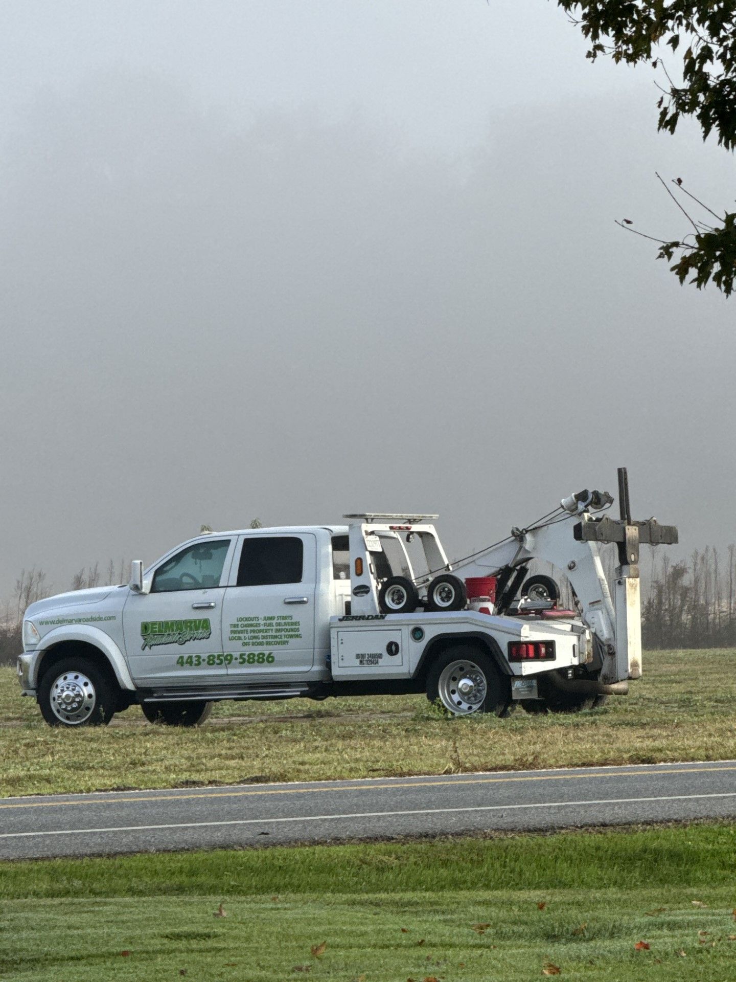 a white tow truck is parked on the side of the road.