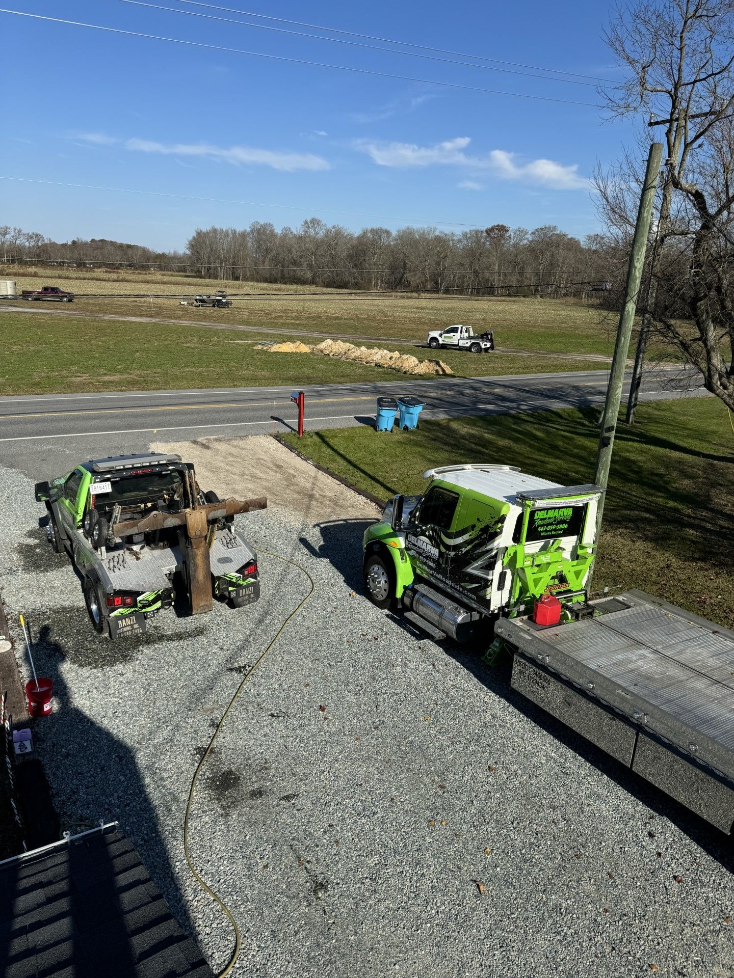 a green truck is parked on the side of the road next to a gravel road.