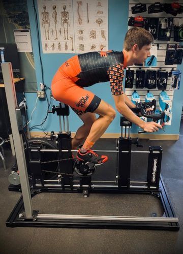 A man is squatting on a machine in a gym.